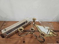 All three items laid out: glitter candles in package, brass 5-arm candelabra, brass sconce with mirror and glass top