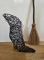 left side view of black wire witch boot with ribbon