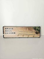 Box front showing product image and BRASS WALL HANGER text