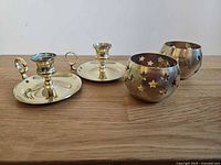 Group view of two brass chambersticks and two brass star-cutout tealight holders