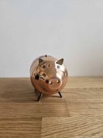 Front view of copper piggy bank showing brass ears, eyes and front legs