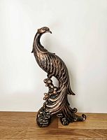 Full front view of copper-tone peacock statue