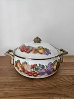 Front view of enamelware pot with fruit motif and brass handles