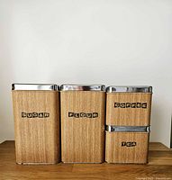 Front view of all four canisters showing labels, faux wood finish and chrome lids