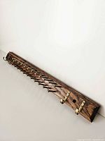 Front perspective of full tie rack showing wood base, brass pegs, hooks and mounting holes