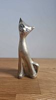 Front view of brass cat figurine showing stylized features