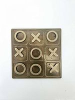 Top view of brass tic-tac-toe board with pieces in place