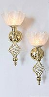 Two matching brass wall sconces mounted on wall, shades illuminated