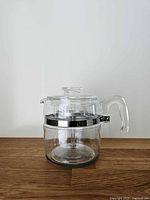 Front left view of glass percolator showing lid, metal band and handle