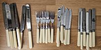 Full set arranged on wooden surface: 6 wide-blade knives, 6 forks, 18 fish knives