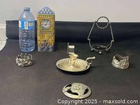 All six metal decorative pieces displayed together for size and style comparison next to a standard water bottle for scale.