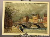 Full view of vintage oil painting with cityscape scene featuring bridge and buildings, contained in a cream colored frame.