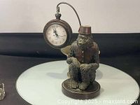 Full view showing the monkey holding knees with the pocket watch clock hanging above.