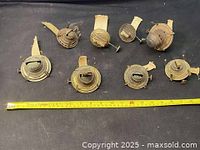 Photo showing the full set of eight vintage brass oil lamp burners laid out next to a measuring tape for scale.