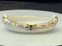 Side view of canoe-shaped porcelain bowl showing floral and ornamental hand painted design.