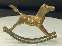 Side view of solid brass rocking horse shaped like a dog on a curved rocking base