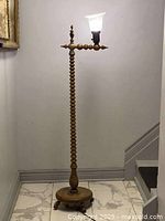 Full view of the solid oak twisted floor lamp with the glass shade lit, showing height and base.