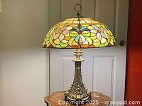 Front view of Tiffany style table lamp with stained glass shade and brass base on a wooden table.