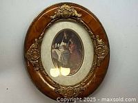 Full view of oval Victorian picture in solid wooden gold-toned frame with ornate decorations.