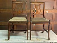 Front view of two vintage Duncan Phyfe style wooden chairs with beige upholstered seats and straight legs.