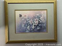 Full frontal image of vintage floral artwork framed in gold wood with glass, depicting white flowers and a butterfly on a blue-purple background.
