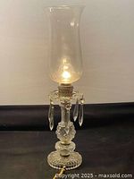 Full view of a vintage glass cut crystal oil lamp with glass chimney, lit to show detail.