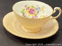 Porcelain teacup and saucer with floral design inside cup and gold rim, scalloped edges