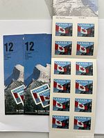 Sheets and booklets of mint unused Canada 42 cent stamps featuring Canadian flag design with blue mountain background on packaging.