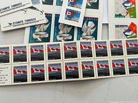 Close-up of multiple Canadian postage stamps in sheets showing 42 cent and 45 cent denominations with Canadian flag and mountainous backgrounds.