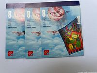 Front view of three sheets of 8 cent Canadian postage stamps with kites on blue sky background, unused and mint.