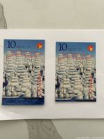 Two closed stamp booklets showing the tall ship shape and denomination 10 cents, with red overprint marks.