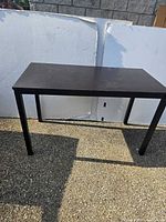 Full view of black desk outside against white backdrop