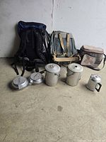 Backpacks, soft cooler and three cookware items displayed