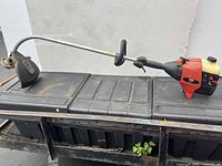 Full view curved-shaft Craftsman Weedwacker 32cc gas string trimmer on bench