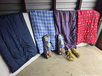 All items lined up: four sleeping bags hanging, two tent bags, two yellow ropes