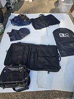 All bags laid out: wheeled garment case, navy duffel, garment bags, briefcase visible