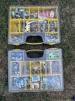 Top view of two yellow plastic organizer cases filled with multiple compartments of assorted electrical connectors and fittings predominantly made of metal.