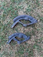 Two black Cole metal pans without handles lying on grass, showing surface rust and embossed numbers.