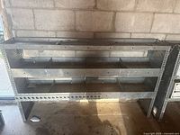 Full front view of the metal shelving unit showing three compartments shelves and overall structure.