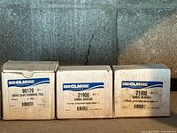 Photo showing three GLM branded boxes containing marine gear parts: one drive gear shimming tool and two gimbal bearings.