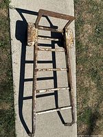 Top view of metal hand truck dolly showing rusted steel frame and solid rubber wheels on concrete surface.