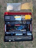 Overview of red toolbox containing drill bits, small accessories, and hand tools