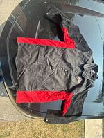 Full jacket laid flat showing red and black suede design, front snap buttons, and pockets.