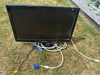 Front view of the Samsung SyncMaster 920NW monitor with power and VGA cables on grass.