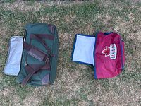 Two cooler totes placed on grass, one green with strap and one red with logo.