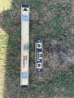 Two spirit levels on grass: one longer metallic gold with three bubbles and 'I Beam' label, and a smaller black and yellow 'Thunder' branded level with two bubble vials.
