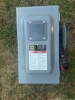 Metal safety switch outdoors with ON/OFF labeled, Square D label and warning info visible