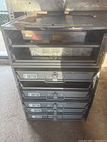 Front view of the cabinet showing the top compartment with clear door and plastic bins, and five labeled drawers below.