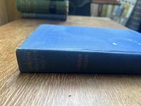 Spine of the book showing title 'London Belongs to Me' by Norman Collins in gold lettering on blue cloth.