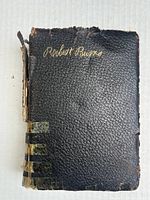 Front cover of the book 'Robert Burns' showing black textured cover with worn edges and gold lettering.